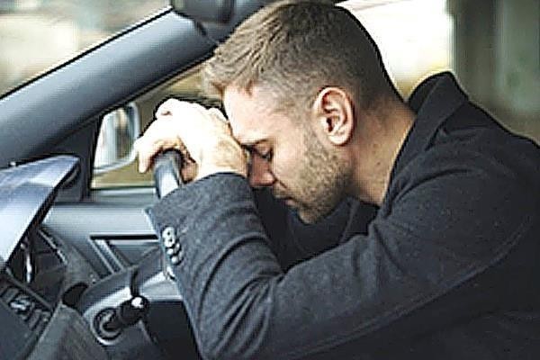 На фото водій у салоні тримається за голову біля керма, що відповідає стану запаморочення та зниження уваги після ліків.