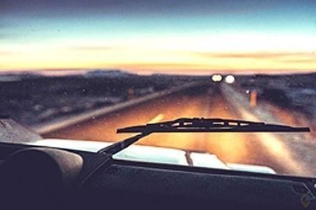 На зображенні дорога в сутінках/уночі, видимість обмежена. Питання про те, як краще спланувати далеку поїздку.