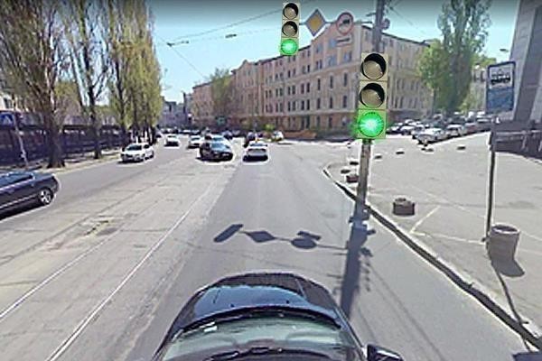 Ви наближаєтесь до перехрестя зі світлофором; на проїзній частині є інтенсивний рух, попереду можливі маневри інших водіїв.