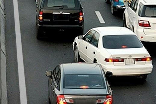 На дорозі кілька автомобілів рухаються в одному напрямку; білий автомобіль праворуч починає перестроювання ліворуч у вашу смугу.