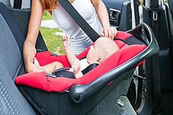 Дитину садять в автокрісло у відчиненому автомобілі. Питання стосується, з якого боку безпечніше й правильно це робити.